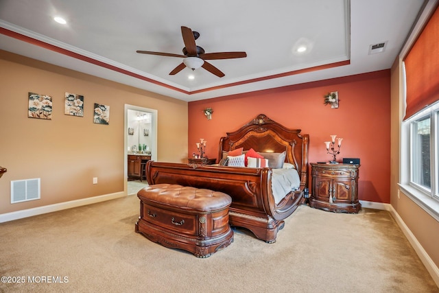 carpeted bedroom with ensuite bath, ceiling fan, crown molding, and a raised ceiling