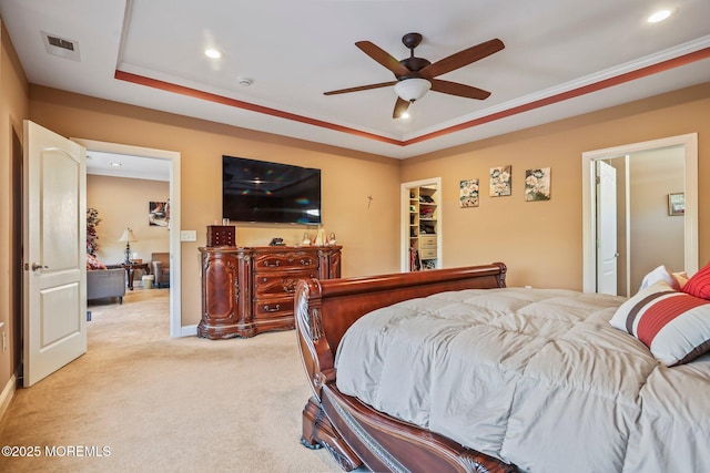 bedroom featuring a walk in closet, light carpet, ornamental molding, a raised ceiling, and ceiling fan