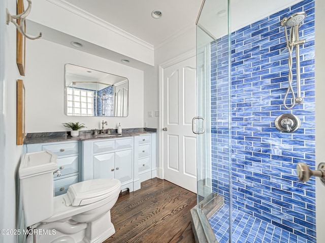 bathroom featuring toilet, crown molding, vanity, a shower with door, and hardwood / wood-style flooring