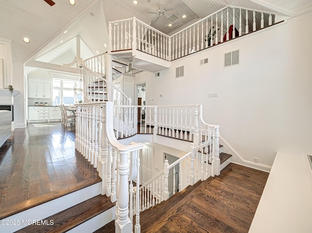 stairs with ceiling fan, wood ceiling, hardwood / wood-style floors, and high vaulted ceiling