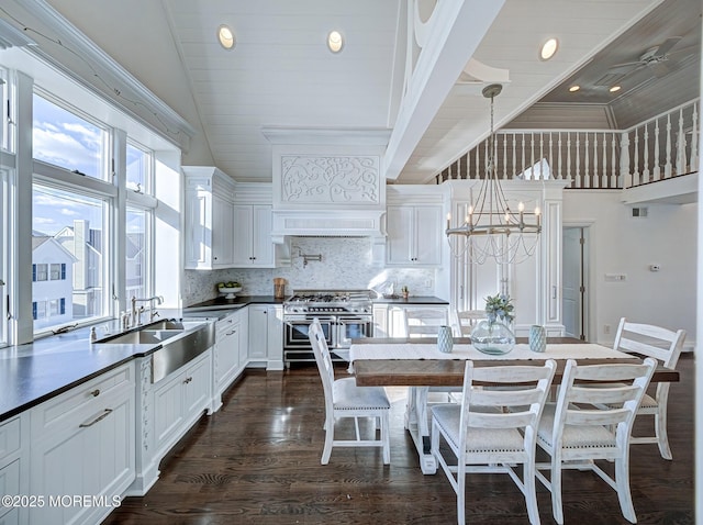 kitchen featuring pendant lighting, double oven range, lofted ceiling, white cabinets, and backsplash