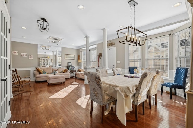 dining area featuring hardwood / wood-style floors, ornamental molding, ornate columns, and a chandelier