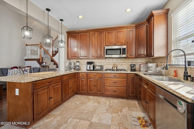 kitchen featuring kitchen peninsula, appliances with stainless steel finishes, tasteful backsplash, pendant lighting, and sink