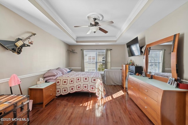 bedroom featuring ceiling fan, dark hardwood / wood-style flooring, crown molding, and a tray ceiling