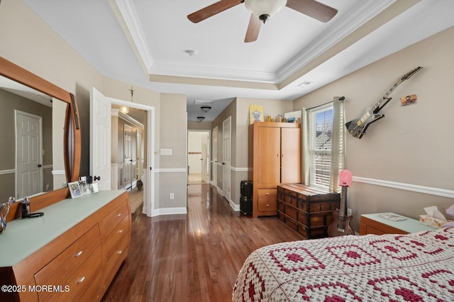 bedroom with ceiling fan, dark hardwood / wood-style flooring, crown molding, and a tray ceiling