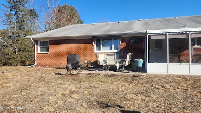 back of property with a lawn, a sunroom, and a patio area