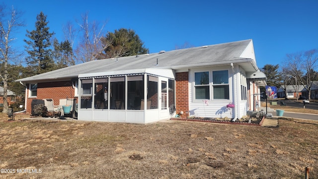 rear view of property featuring a lawn and a sunroom