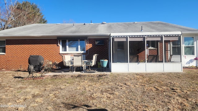 back of property featuring a patio, a yard, and a sunroom