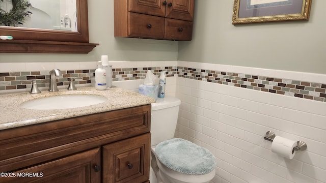 bathroom featuring toilet, tile walls, and vanity