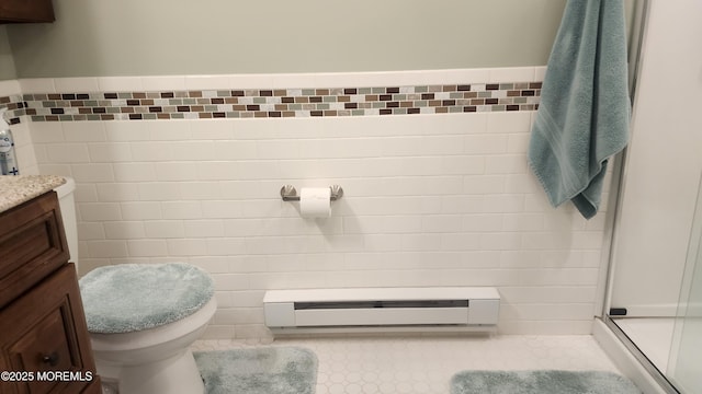 bathroom featuring toilet, walk in shower, vanity, tile walls, and a baseboard heating unit