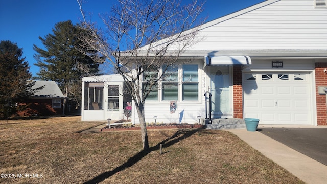 view of front of property featuring a front yard, a sunroom, and a garage