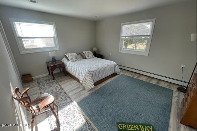 bedroom featuring hardwood / wood-style floors and a baseboard heating unit