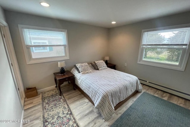 bedroom with light hardwood / wood-style floors and a baseboard radiator