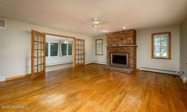 unfurnished living room featuring a fireplace, french doors, light hardwood / wood-style flooring, and a baseboard heating unit