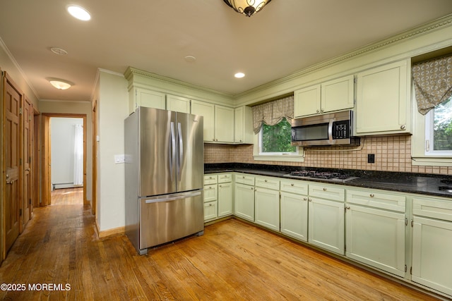 kitchen with stainless steel appliances, a baseboard radiator, tasteful backsplash, and light hardwood / wood-style floors