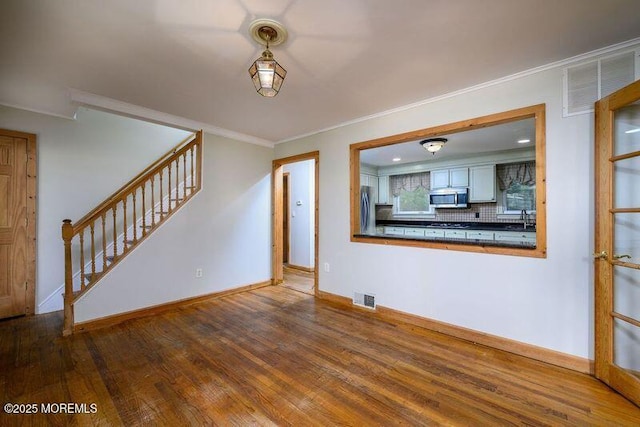 unfurnished living room featuring crown molding, sink, and wood-type flooring