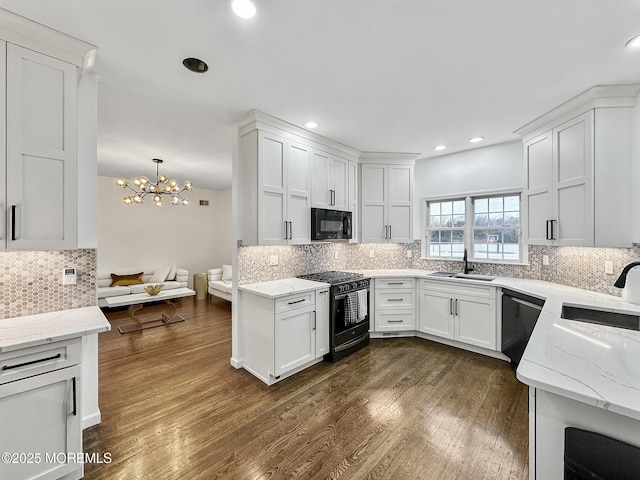 kitchen with white cabinetry, dark wood-type flooring, a chandelier, pendant lighting, and black appliances