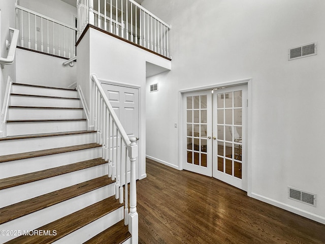 stairs with hardwood / wood-style floors, a high ceiling, and french doors