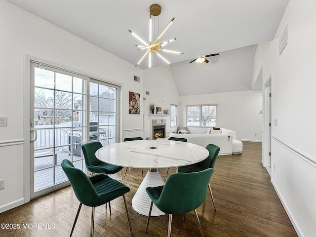 dining area featuring dark hardwood / wood-style flooring, high vaulted ceiling, and ceiling fan with notable chandelier