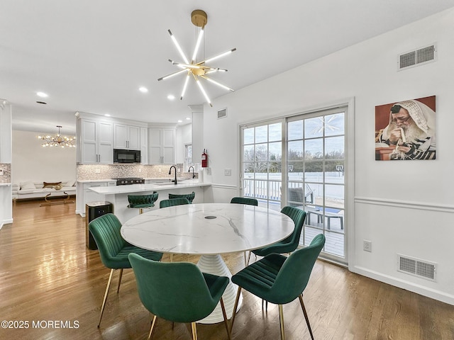 dining room with light hardwood / wood-style flooring, an inviting chandelier, and sink