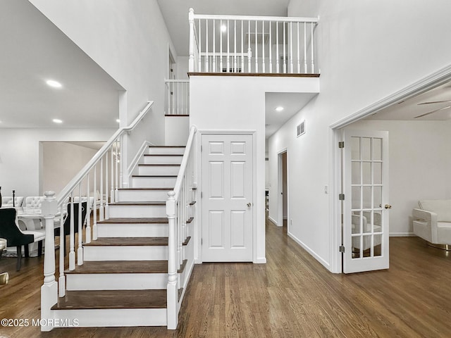 staircase with hardwood / wood-style floors and a high ceiling