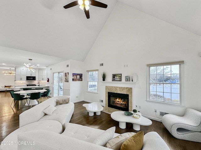 living room with ceiling fan, sink, a high end fireplace, high vaulted ceiling, and dark hardwood / wood-style floors