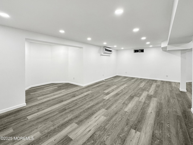 basement with dark hardwood / wood-style flooring and an AC wall unit