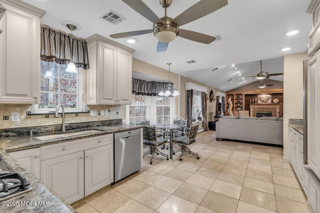 kitchen with sink, dishwasher, vaulted ceiling, and plenty of natural light