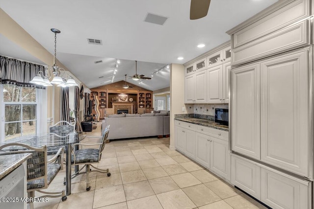 kitchen featuring pendant lighting, dishwashing machine, lofted ceiling, white cabinets, and black microwave