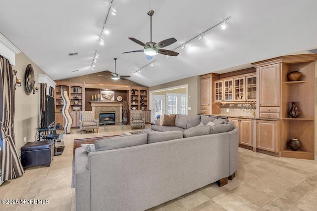 living room with a fireplace, ceiling fan, and vaulted ceiling