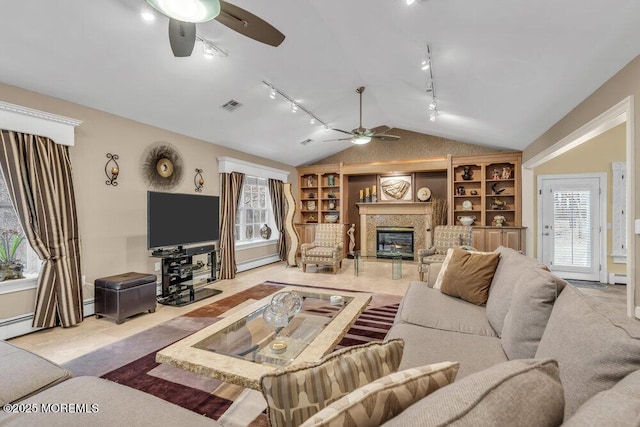 living room with lofted ceiling, a high end fireplace, baseboard heating, and plenty of natural light