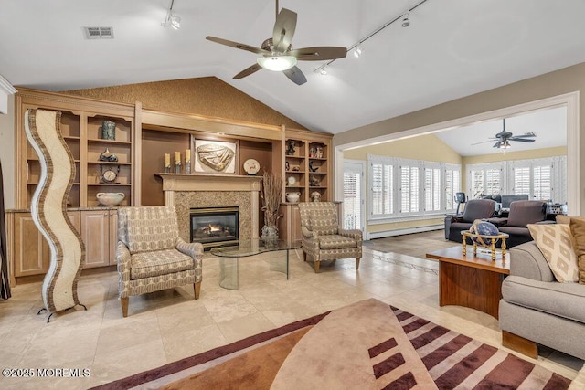 tiled living room with rail lighting, a premium fireplace, ceiling fan, lofted ceiling, and a baseboard radiator