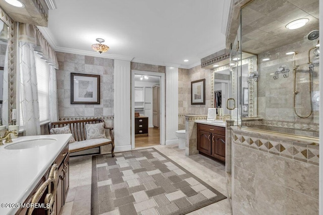 bathroom with toilet, an enclosed shower, vanity, and tile walls