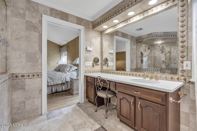 bathroom featuring tile walls, vanity, ornamental molding, and a shower with shower door