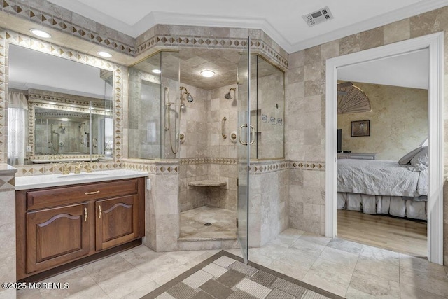 bathroom with ornamental molding, vanity, tile walls, and a shower with shower door