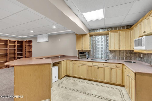 kitchen with light brown cabinetry, decorative backsplash, and sink