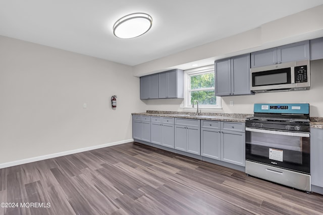 kitchen featuring gray cabinetry, sink, light hardwood / wood-style flooring, and appliances with stainless steel finishes