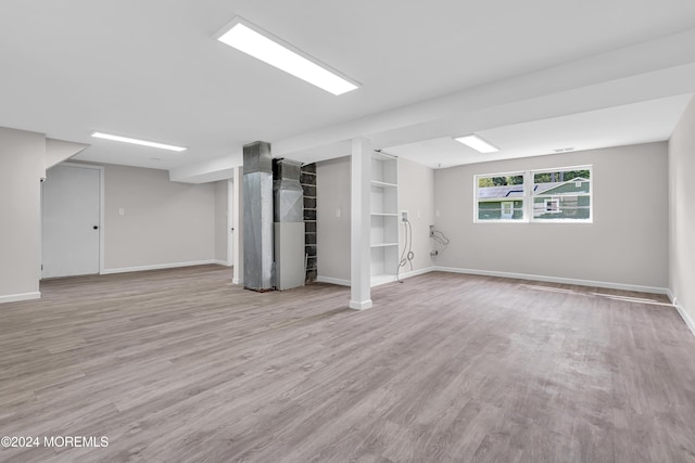 basement with built in shelves and light hardwood / wood-style flooring