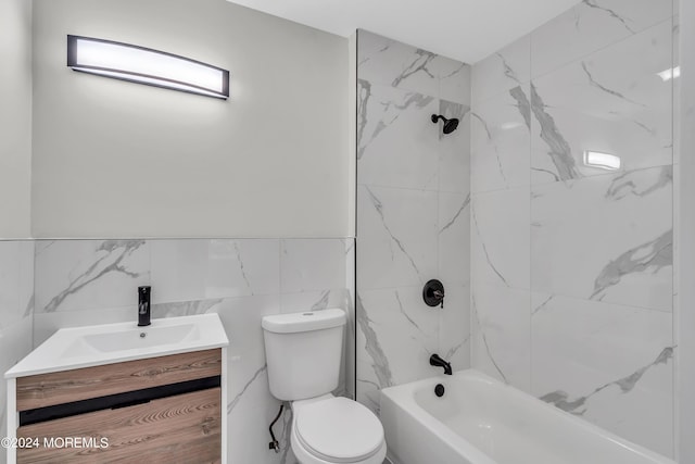 full bathroom featuring toilet, vanity, tile walls, and tiled shower / bath