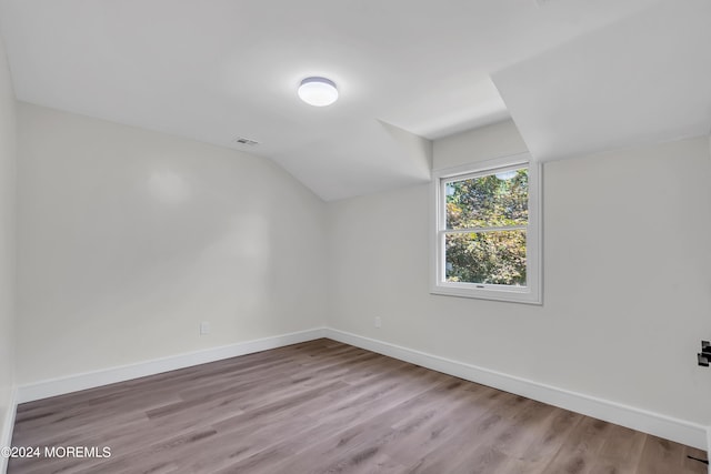 additional living space featuring light hardwood / wood-style floors and vaulted ceiling