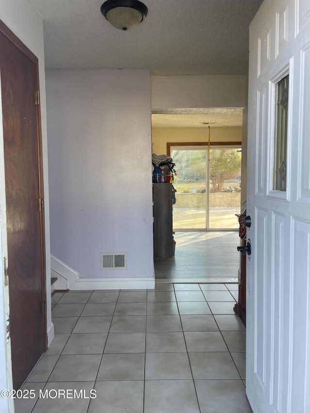 hall featuring a textured ceiling and light tile patterned flooring