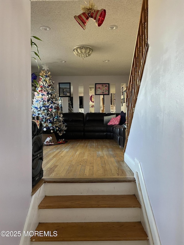 stairway with a textured ceiling and wood-type flooring