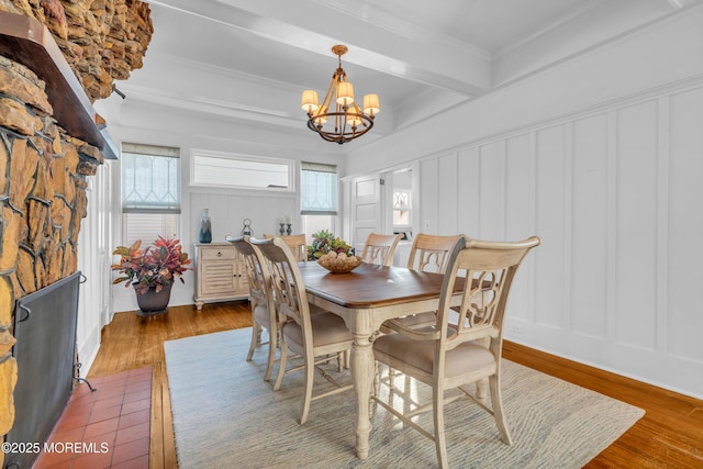 dining room with a wealth of natural light, beam ceiling, a chandelier, and hardwood / wood-style flooring