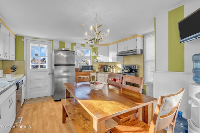 dining space featuring a notable chandelier, ornamental molding, and light hardwood / wood-style flooring