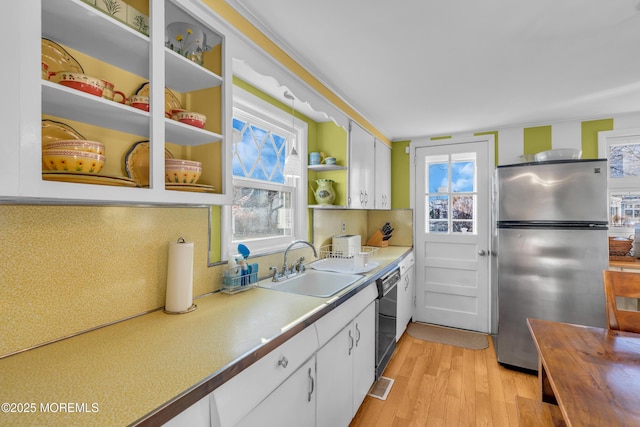 kitchen featuring white cabinetry, sink, plenty of natural light, stainless steel fridge, and light wood-type flooring