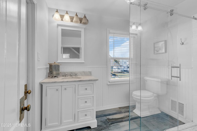 bathroom featuring toilet, a shower with shower door, and vanity