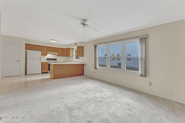 kitchen with ceiling fan, stainless steel range oven, kitchen peninsula, white fridge, and light carpet