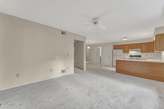 unfurnished living room featuring light colored carpet, ceiling fan, and sink