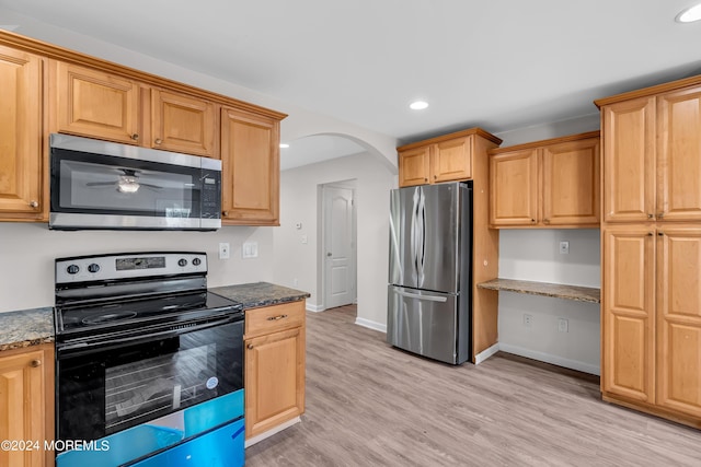 kitchen featuring ceiling fan, light hardwood / wood-style flooring, dark stone counters, and appliances with stainless steel finishes