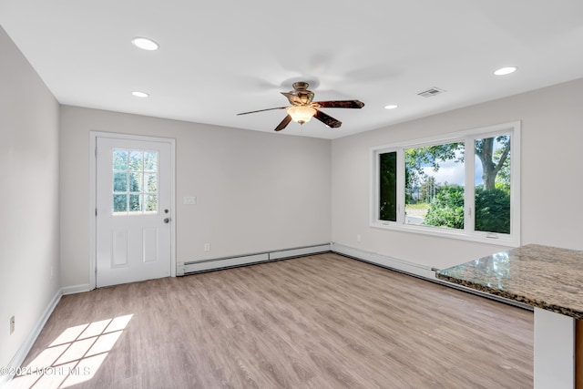 unfurnished living room featuring plenty of natural light, ceiling fan, light wood-type flooring, and baseboard heating